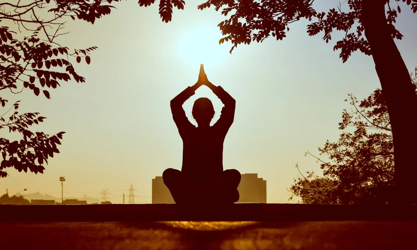 Silhouette meditating at golden sunset