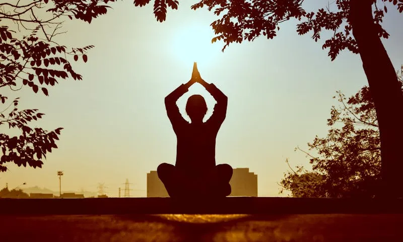 Silhouette meditating at sunset
